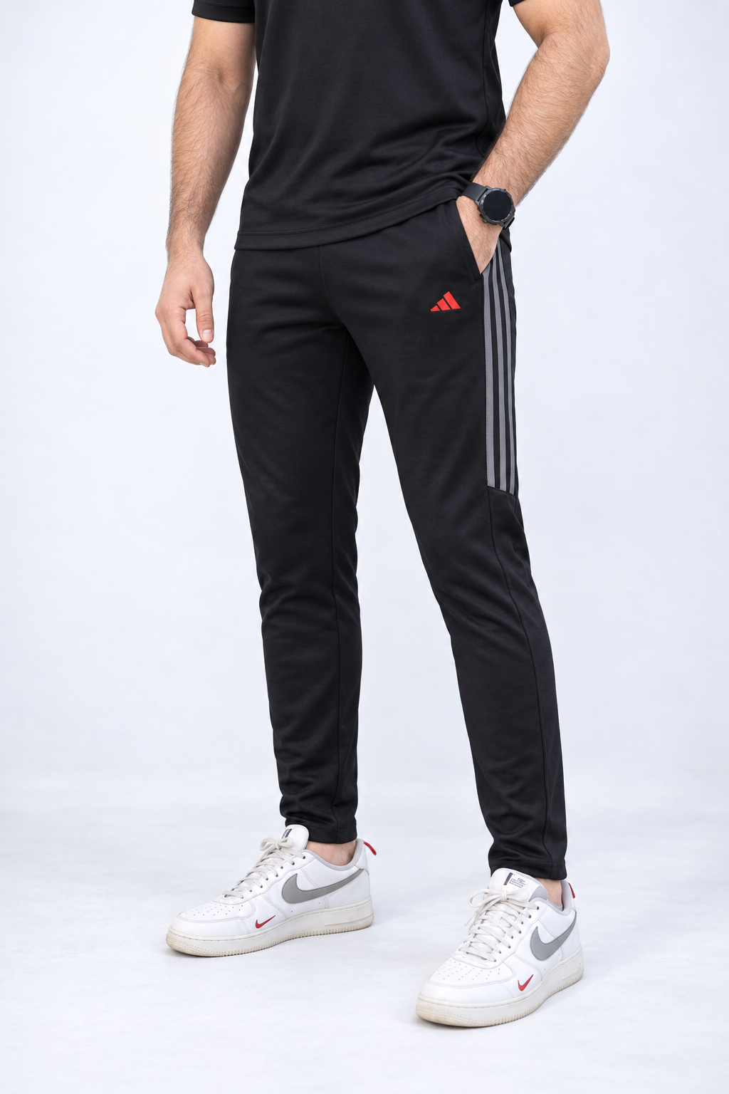 ADI black tracksuit trousers detail with three grey upper-leg stripes and red thigh logo